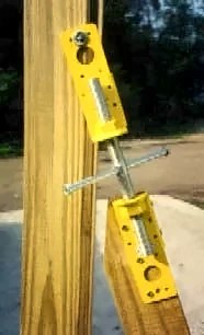 Yellow Scroogeclamp bracket screwed to a wood post with the drawbar and handle angled toward the ground